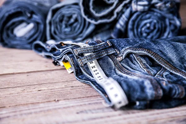Jeans und Zentimeter auf einem hölzernen Hintergrund. Kleidung — Stockfoto