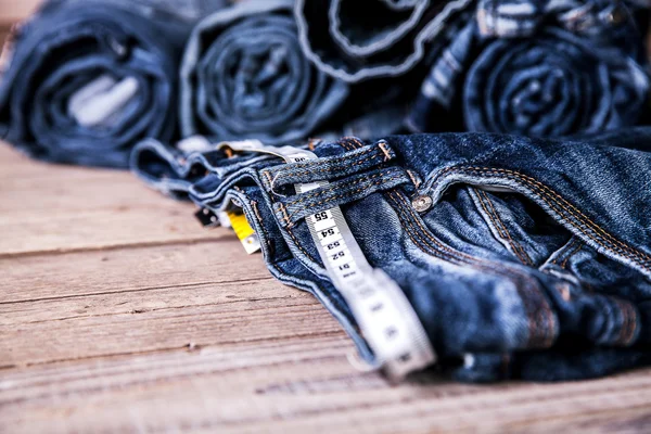 Jeans und Zentimeter auf einem hölzernen Hintergrund. Kleidung — Stockfoto