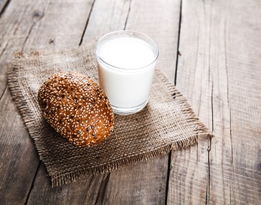 Bir bardak süt ve ahşap arka plan bir çörek. Gıda