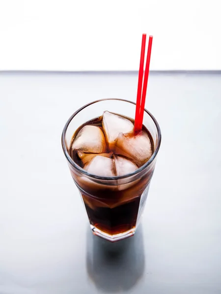 Cola in un bicchiere con ghiaccio con tubo rosso. bevande analcoliche — Foto Stock