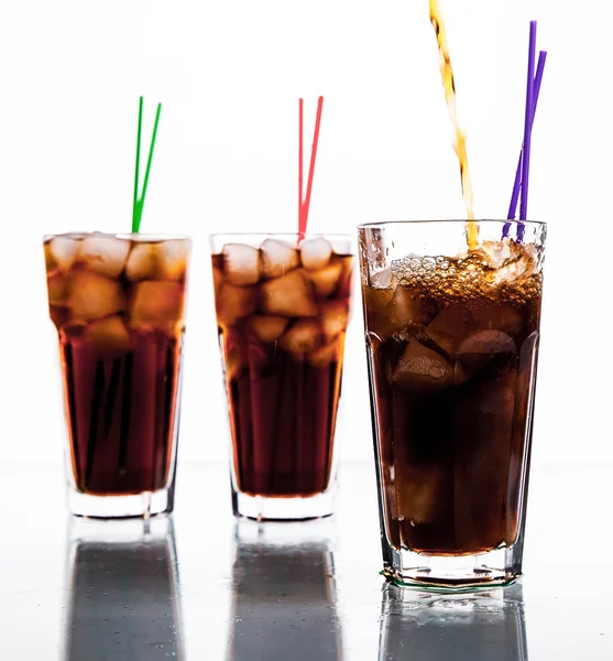 Tres vasos de cola con hielo y pajitas sobre fondo blanco . — Foto de Stock