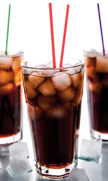 Drie glazen cola met ijs en rietjes op een witte achtergrond. — Stockfoto