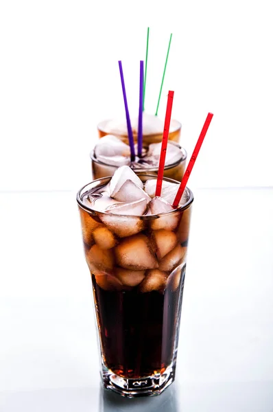 Tre bicchieri di cola con ghiaccio e cannucce su fondo bianco . — Foto Stock