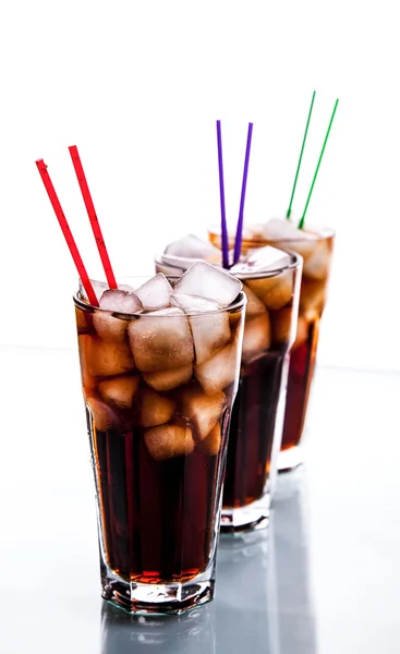 Tre bicchieri di cola con ghiaccio e cannucce su fondo bianco . — Foto Stock