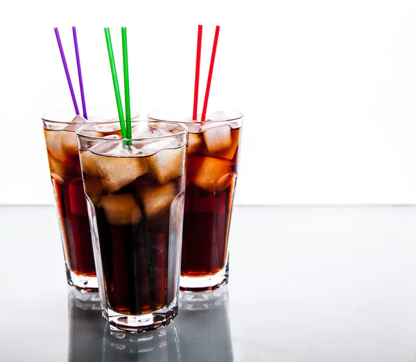 Tres vasos de cola con hielo y pajitas sobre un fondo blanco. refrescos — Foto de Stock