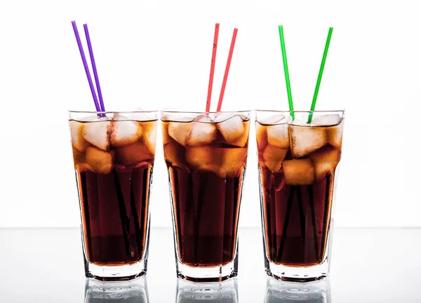 Tre bicchieri di cola con ghiaccio e cannucce su fondo bianco . — Foto Stock