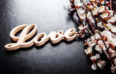 siyah bir arka plan ve ahşap bir işareti ile kelime aşk çiçek