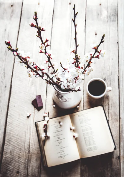Offenes Jahrgangsbuch mit Blütenzweig des Kirschbaums auf Holztisch mit schöner Vase. eine Tasse Kaffee — Stockfoto