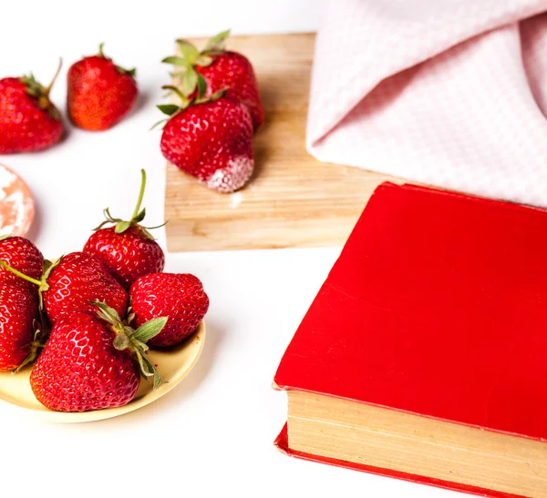 Erdbeeren auf einem roten Buch in einem gelben Teller. Früchte — Stockfoto