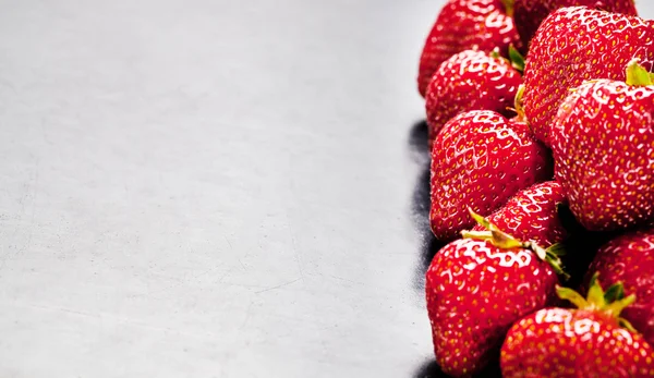 En massa jordgubbar på sidan med ett tomt utrymme för text. frukt — Stockfoto