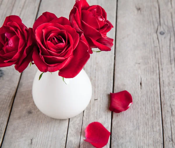Червона троянда у вазі на дерев'яному столі — стокове фото