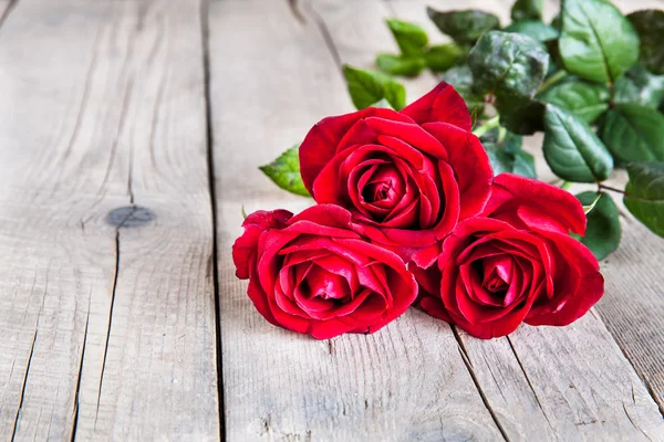 Červené růže na dřevěném pozadí — Stock fotografie
