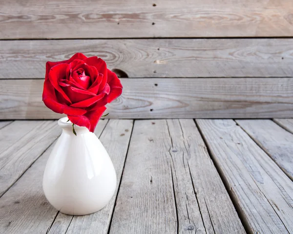 Rosa vermelha em vaso na mesa de madeira — Fotografia de Stock