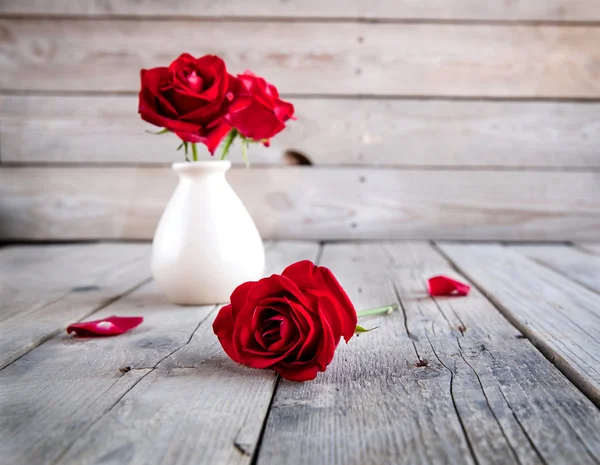 Rosa roja en jarrón sobre mesa de madera — Foto de Stock