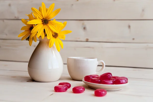 Um belo arranjo de flores amarelas, doces e xícara de cof — Fotografia de Stock