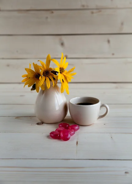 Un bel arrangement de fleurs jaunes, des bonbons et une tasse de café — Photo