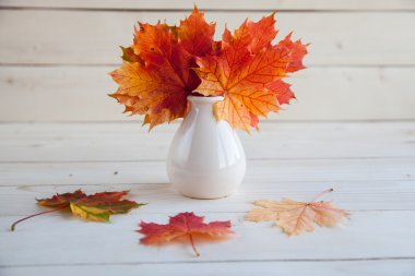 Sonbahar akçaağaç yaprakları grup eski ahşap zemin üzerine vazoda