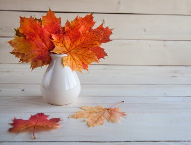 Sonbahar akçaağaç yaprakları grup eski ahşap zemin üzerine vazoda