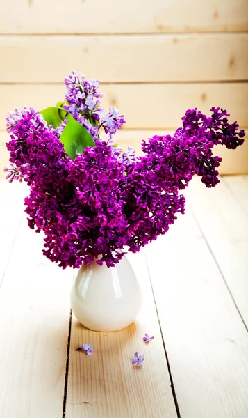 Bouquet lilla in brocca di ceramica contro una parete di legno bianco . — Foto Stock
