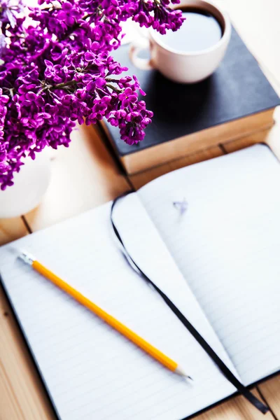 Belo lilás na mesa de escritório com um livro e uma xícara de café e caderno — Fotografia de Stock
