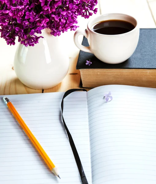 Liliac frumos pe birou cu o carte și o ceașcă de cafea a — Fotografie, imagine de stoc
