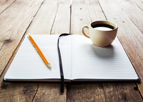 Caneta notebook e xícara de café em mesa de madeira — Fotografia de Stock