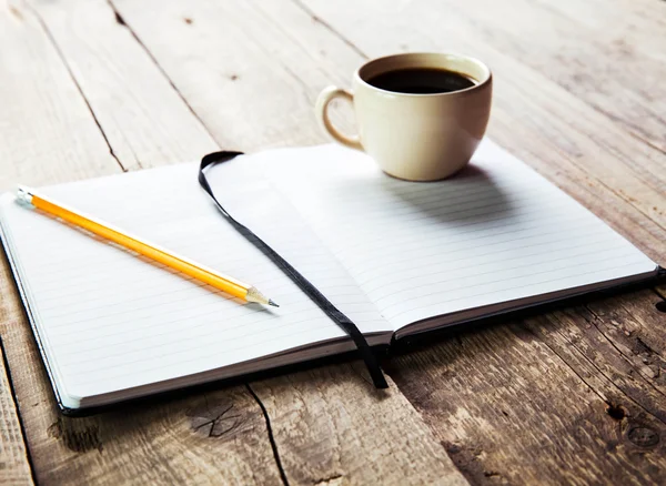 Caneta notebook e xícara de café em mesa de madeira — Fotografia de Stock