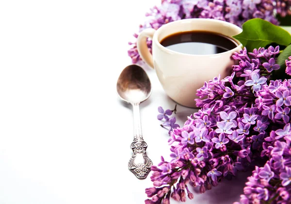 Black coffee in a cup, a spoon and fresh lilac flowers — Stock Photo, Image