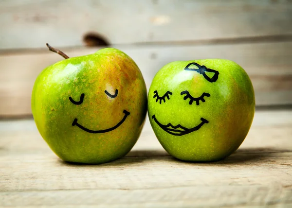 fruit. Face on a green apple. Couple in love. Wooden background