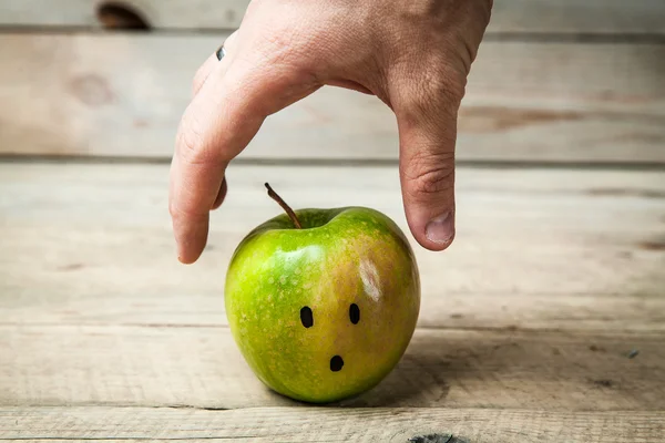 Mains atteignant pour une pomme verte sur fond en bois — Photo