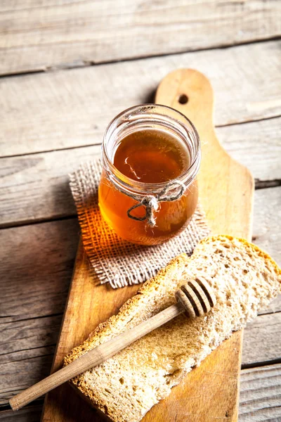 在一个罐子里的蜂蜜，一片面包 图库图片