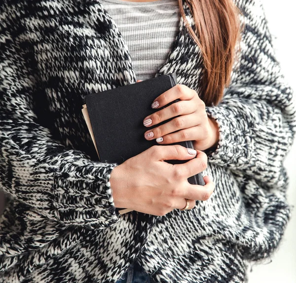 Feliz estudiante mujer sosteniendo un libro en pantalones vaqueros rotos —  Fotos de Stock