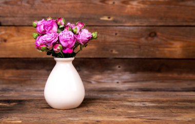 ahşap arka plan üzerinde bir vazoda pembe gül. çiçekler