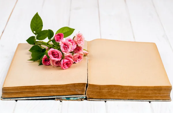 Rose su un vecchio libro su sfondo bianco in legno. fiori — Foto Stock