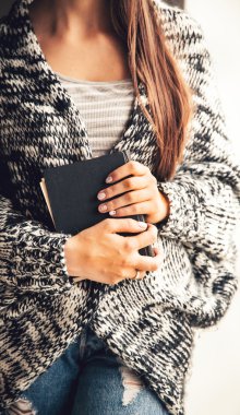 mutlu kız öğrenci bir kitap yırtık kot pantolon tutarak