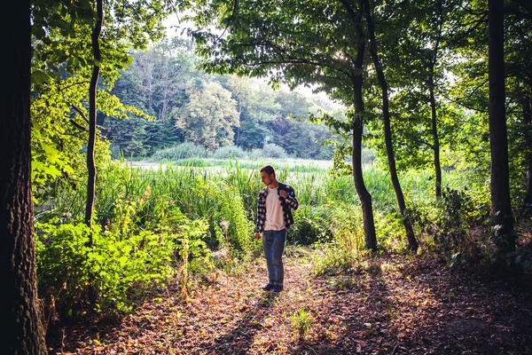 Portret van jonge knappe man lopen in het bos — Stockfoto