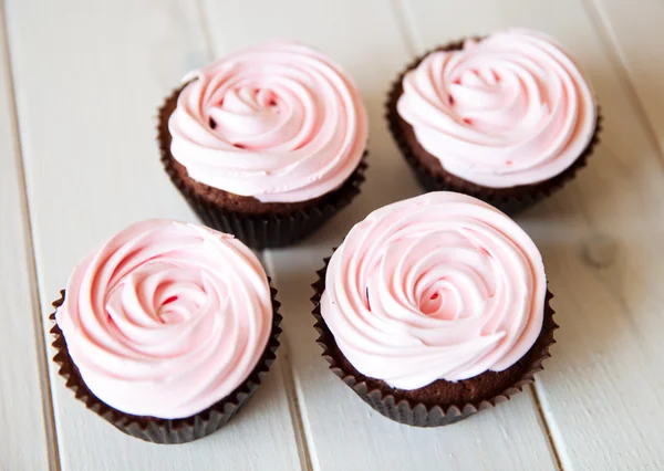 Cupcakes cor-de-rosa como uma rosa no fundo de madeira branco — Fotografia de Stock