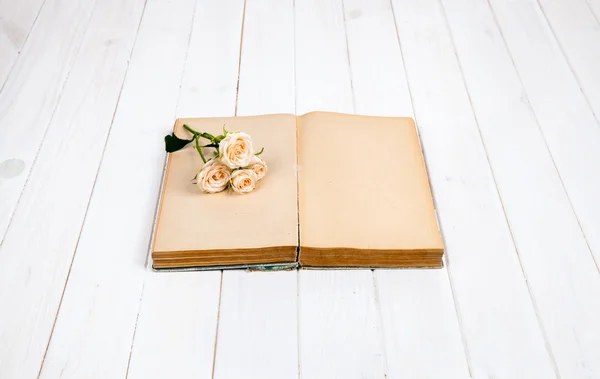 Rozen op een oud boek op witte houten achtergrond. bloemen — Stockfoto