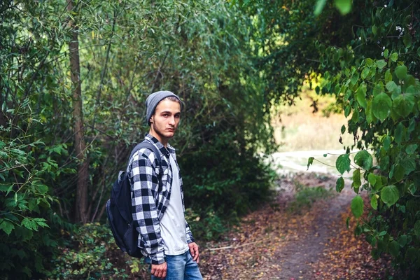 Retrato de homem bonito jovem com mochila passeio de andarilho na floresta — Fotografia de Stock