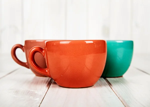 Tazza di caffè a tre colori su sfondo bianco in legno — Foto Stock