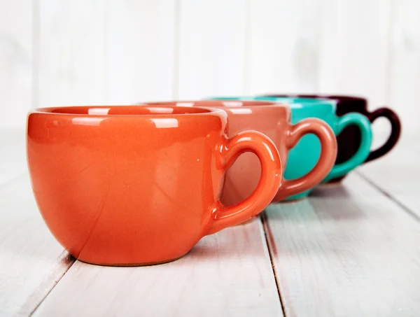 Tazas de colores sobre un fondo blanco de madera. concepto de café —  Fotos de Stock