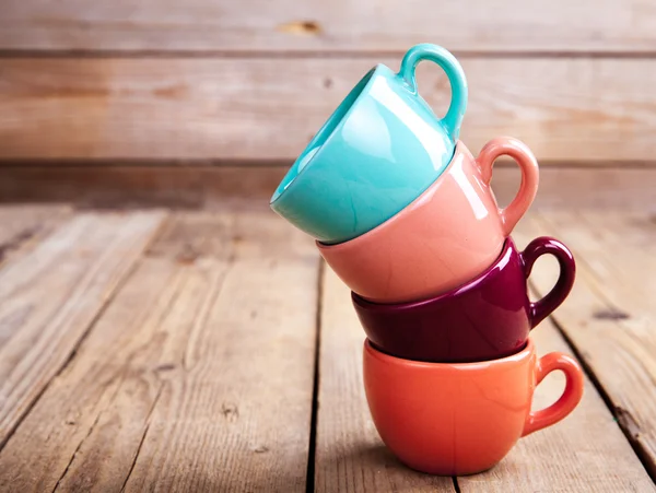 Tasses à café colorées sur table en bois sur fond grunge — Photo