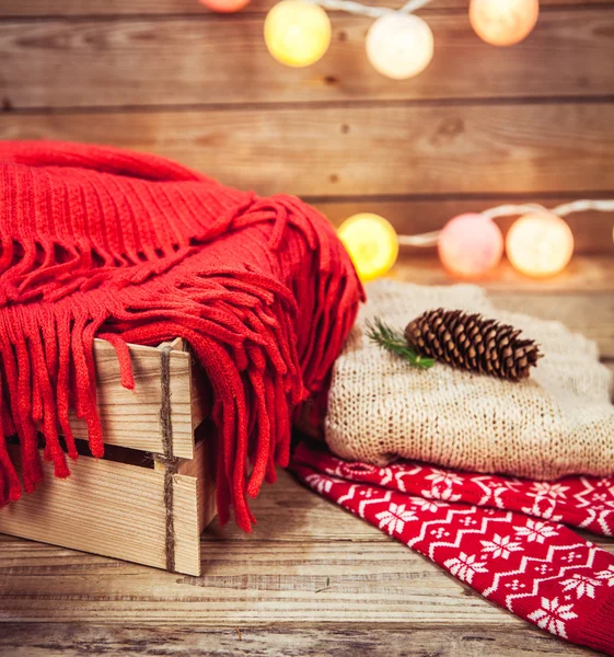 Set de Navidad. Manta caliente, suéter, calcetines, guirnalda y un bulto en el fondo de madera —  Fotos de Stock