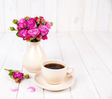 bir fincan kahve Beyaz ahşap zemin üzerinde taze çiçek gül