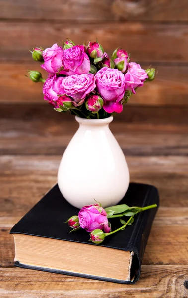 Rose rosa in un vaso, booke su sfondo di legno. fiori — Foto Stock