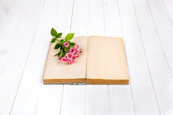 Rosas em um livro antigo sobre fundo de madeira branca. flores — Fotografia de Stock