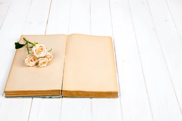 Rozen op een oud boek op witte houten achtergrond. bloemen — Stockfoto