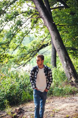 Sırt çantası avare ile genç yakışıklı adam portresi ormanın içinde yürümek