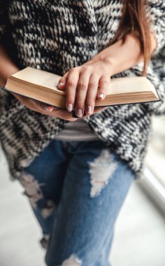 mutlu kız öğrenci bir kitap yırtık kot pantolon tutarak