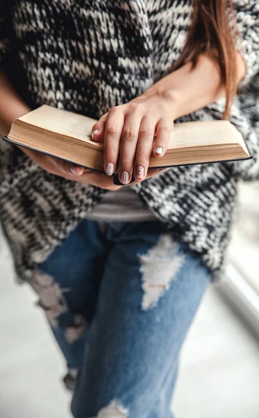 mutlu kız öğrenci bir kitap yırtık kot pantolon tutarak